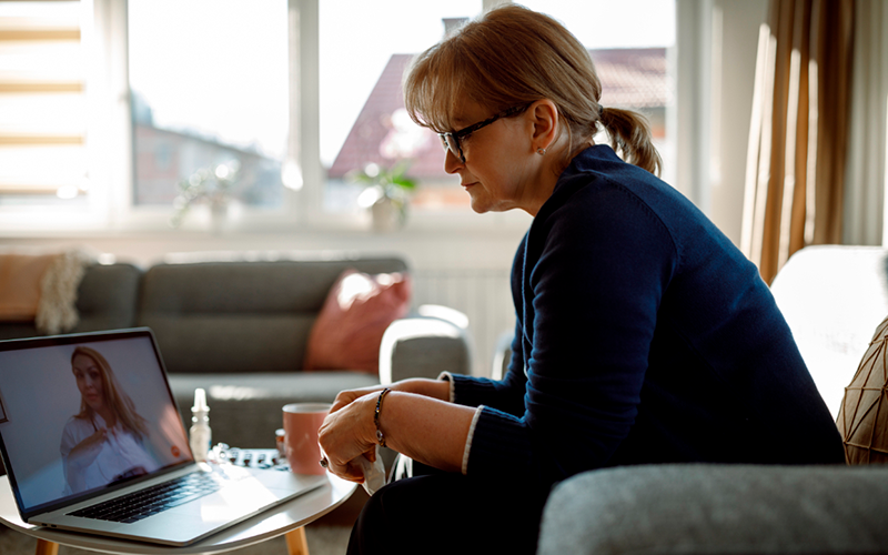 Dame voor computer in gesprek met zorgprofessional