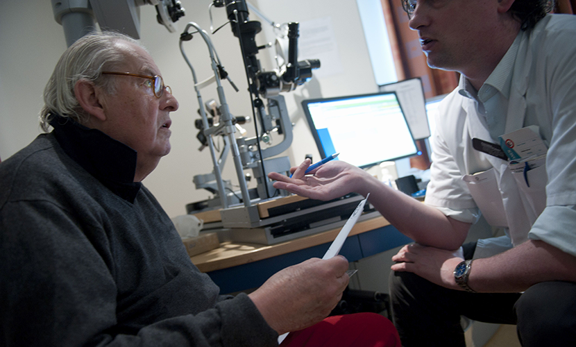 Zorgprofessional spreekt met oudere man bij de opticien