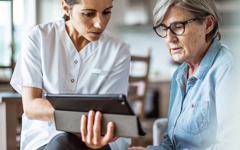 Zorgprofessional laat op tablet patiënt informatie-zien