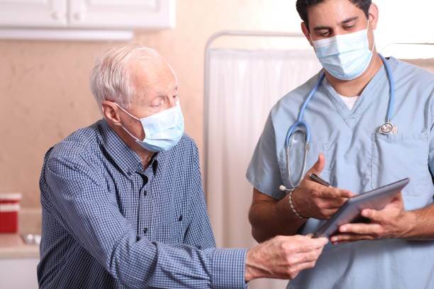 Man met mondkapje kijkt mee op tablet zorgprofessional